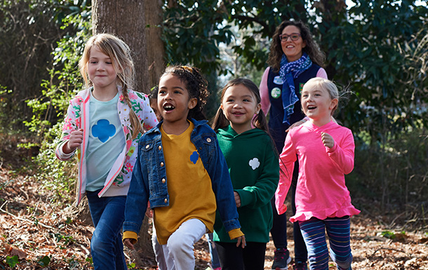 group of young girl scout daisies hiking with adult volunteer group of young girl scout daisies hiking with adult volunteer